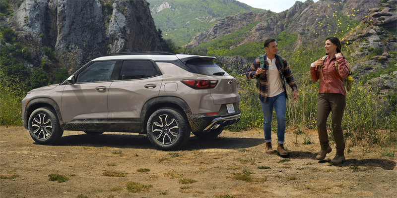 Happy couple standing near Chevrolet Trailblazer on campgrounds